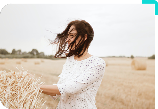 A woman in white shirt standing on top of dry grass.