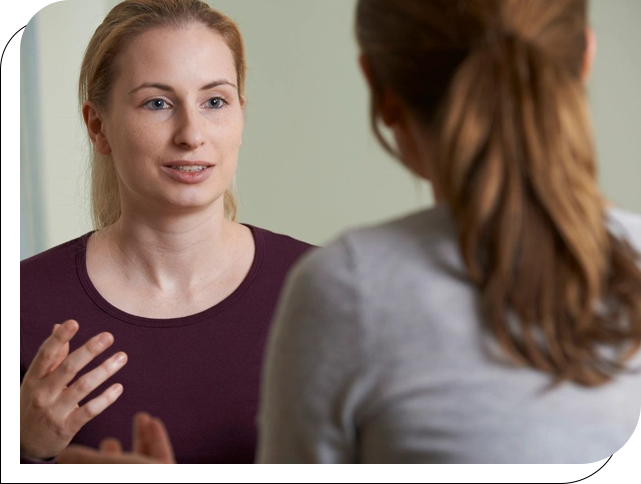 A woman talking to another person in front of a mirror.